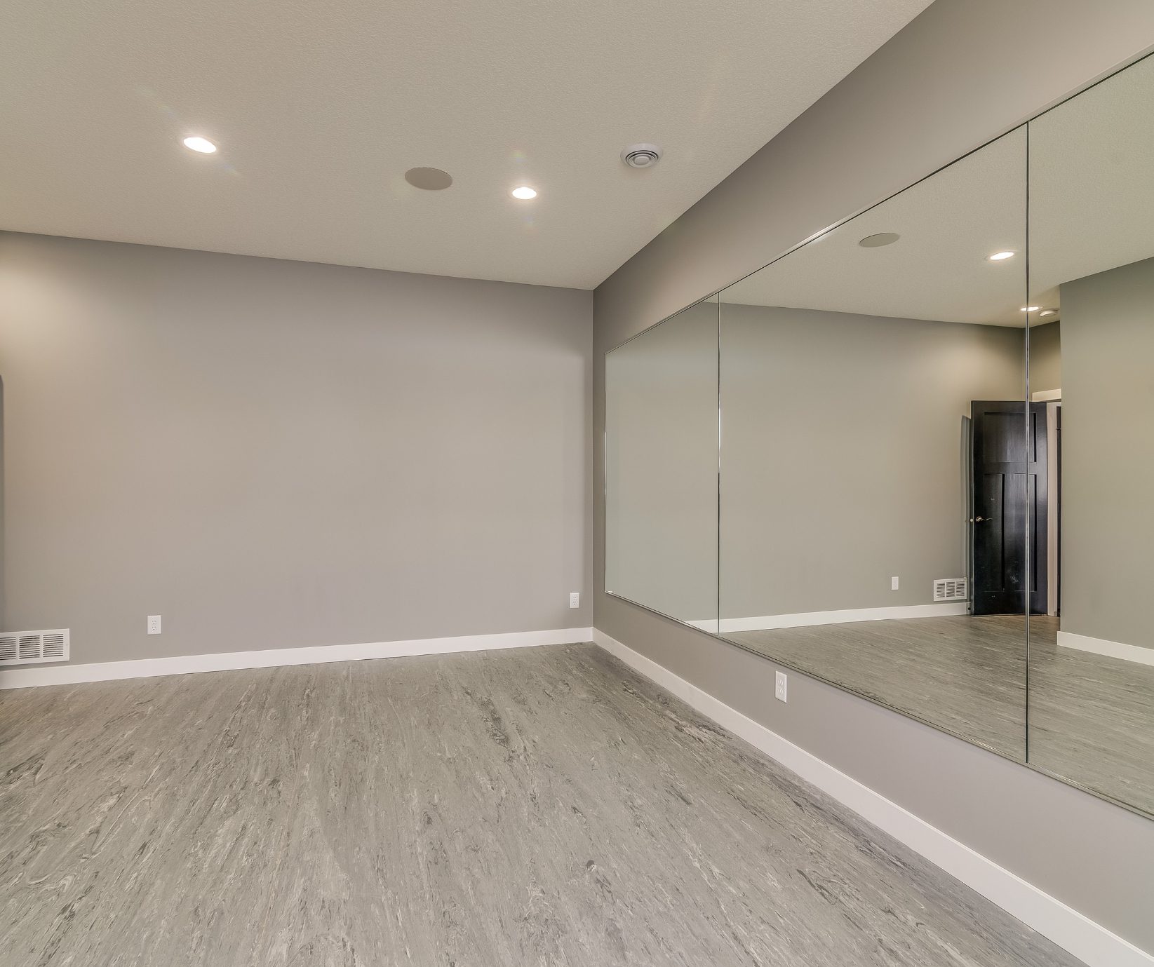 Finished basement in Tolland CT Finished basement in Tolland County CT with gray vinyl flooring, recessed lighting, and large wall mirror.